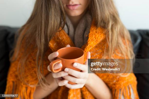 crop view of young woman sitting on couch holding orange mug - hot drink stock pictures, royalty-free photos & images