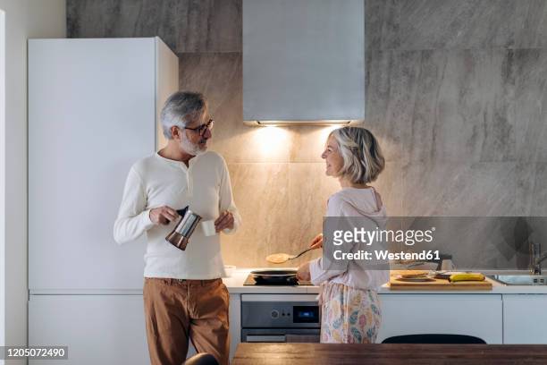 mature couple in kitchen at home in the morning - espresso mann stock-fotos und bilder