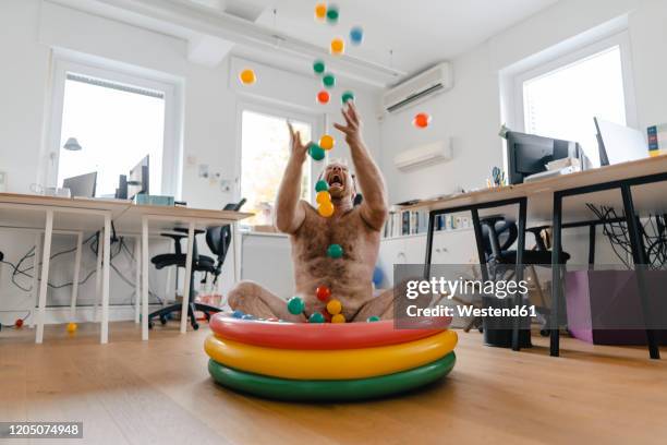 crazy businessman sitting in wading pool in office playing with balls - unleash creativity stock pictures, royalty-free photos & images