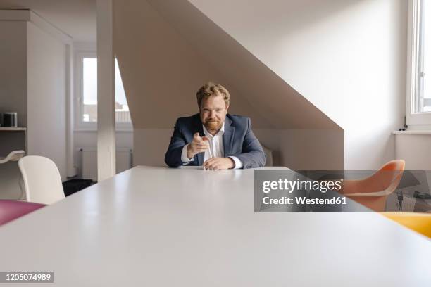 confident businessman sitting at desk in office pointing his finger - different perspective stock-fotos und bilder