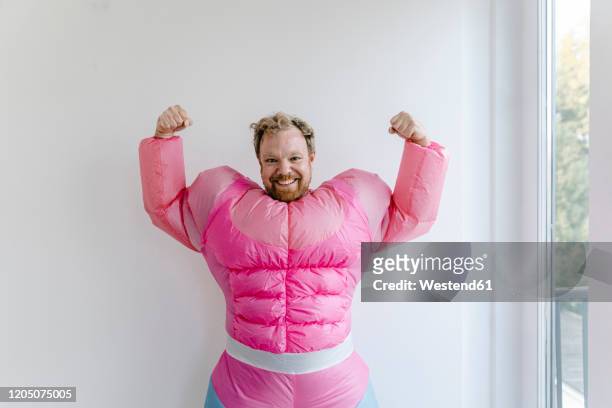 proud man wearing pink bodybuilder costume flexing his muscles - humor stock pictures, royalty-free photos & images