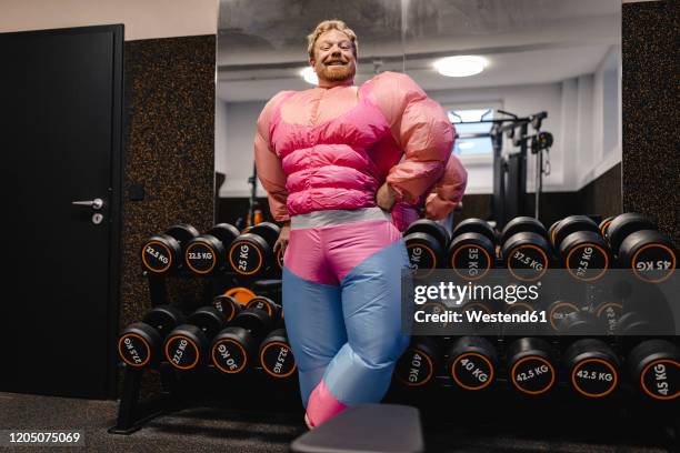 proud man wearing pink bodybuilder costume in gym - comic image of man with gun in desert stockfoto's en -beelden