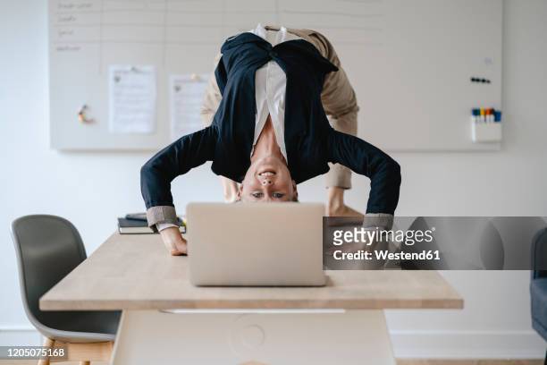 young businesswoman practicing yoga on desk in office - office yoga stock pictures, royalty-free photos & images