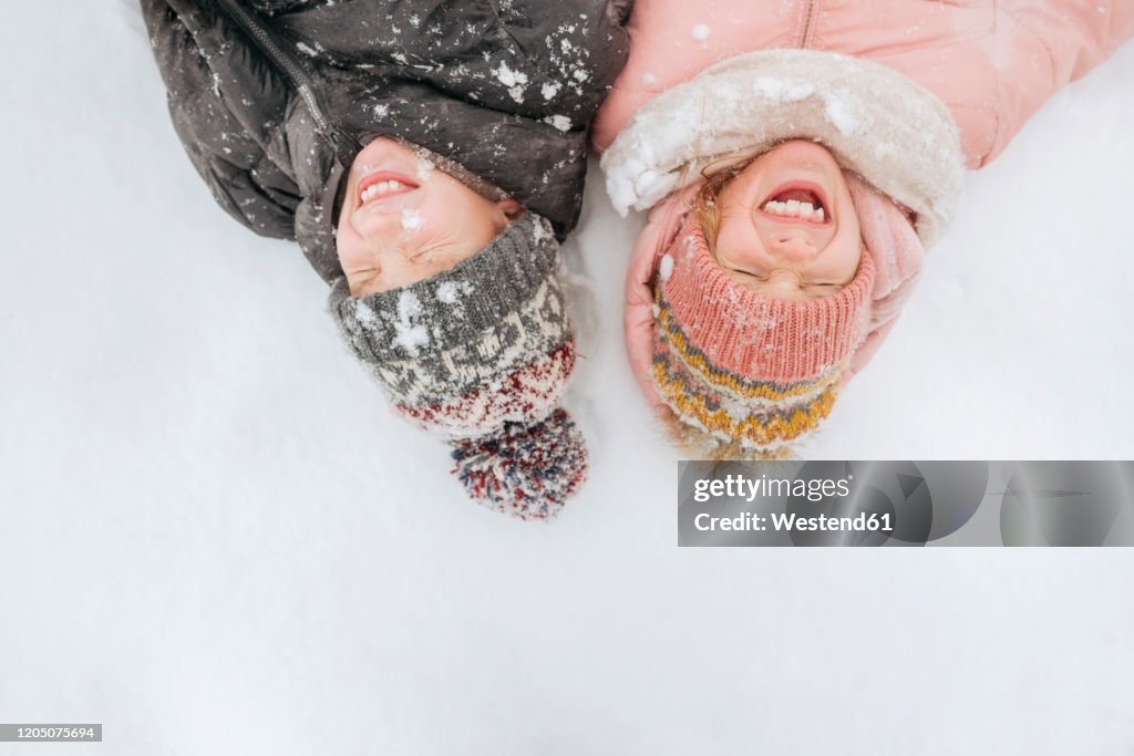 Portrait of two siblings lying on snow
