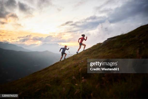 man and woman running uphill in the mountains - carrera de campo través fotografías e imágenes de stock