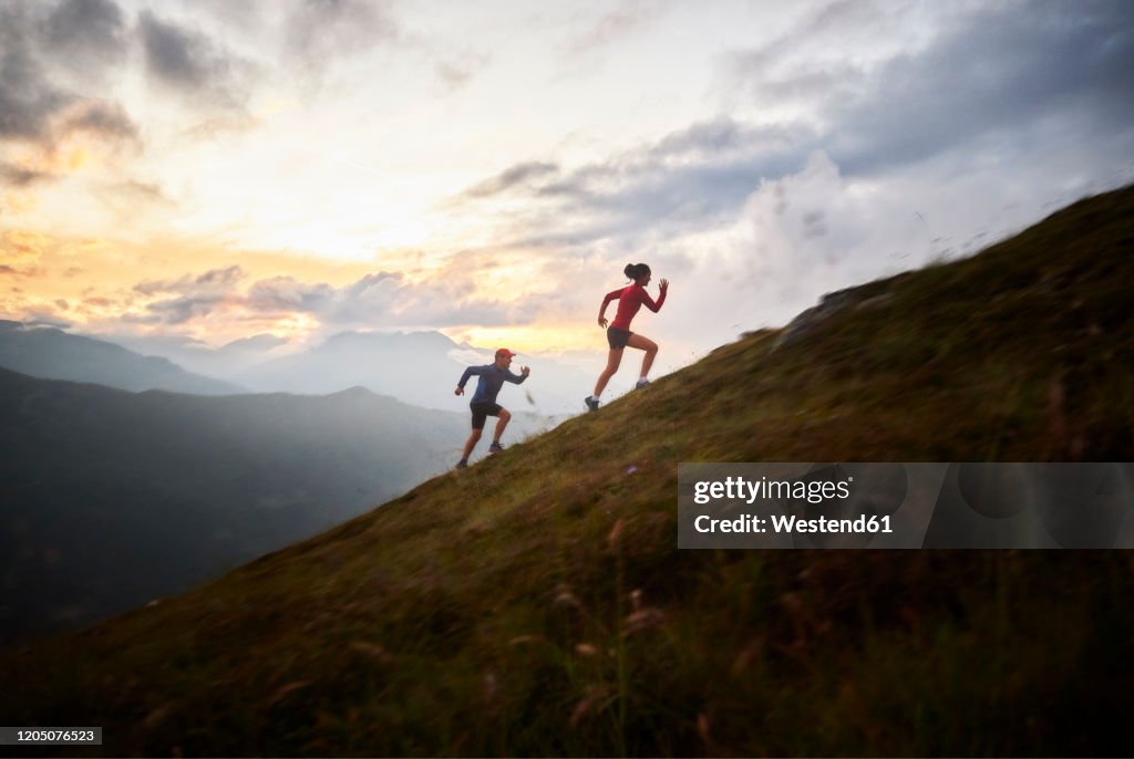 Man and woman running uphill in the mountains