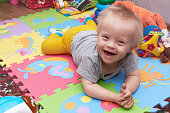 Closeup of happy smiling baby boy crawling on colorful playmat. child on a play mat with toys. smiling child with down syndrome.