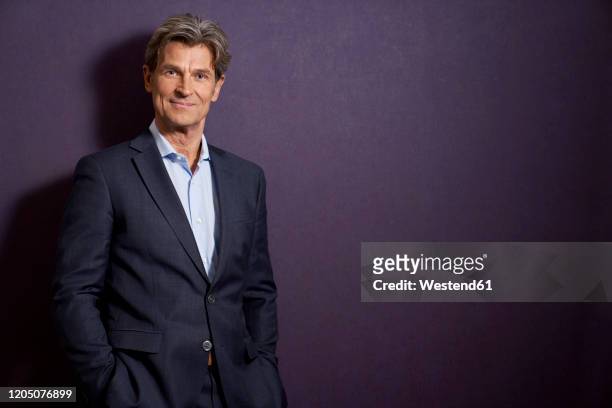 portrait of confident businessman in front of a purple wall - eleganz stock-fotos und bilder