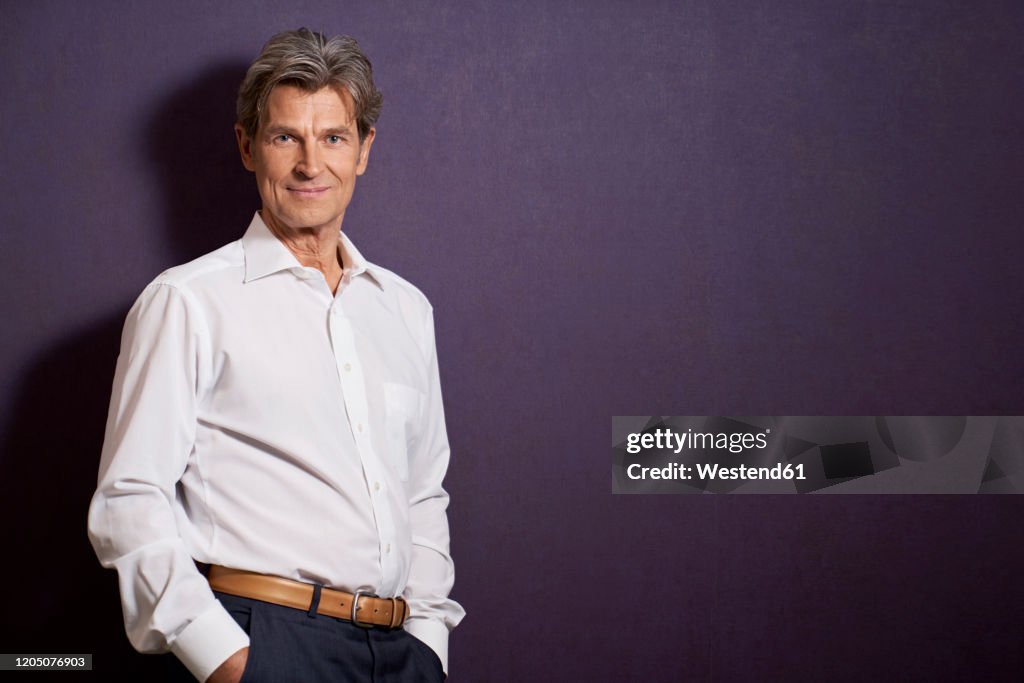 Portrait of confident businessman in front of a purple wall