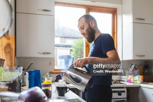 man in the kitchen preparing a tea - tea cup stock pictures, royalty-free photos & images