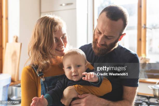 happy affectionate family in the kitchen at home - mum dad and baby fotografías e imágenes de stock