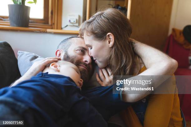 affectionate family on the sofa with sleeping little son - tired couple stock pictures, royalty-free photos & images