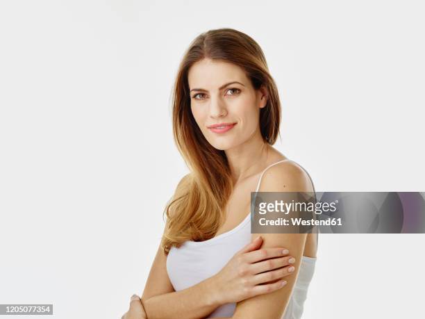 portrait of smiling woman with long hair against white background - mid adult stock-fotos und bilder