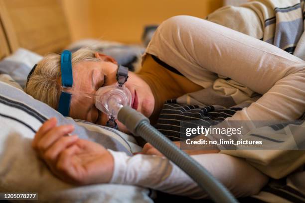 woman sleeping with cpap mask because of obstructive sleep apnea - nose mask stock pictures, royalty-free photos & images