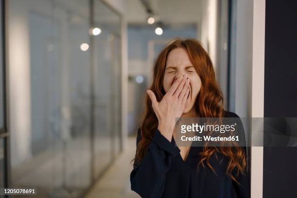 redheaded woman yawning on office floor - yawn office stockfoto's en -beelden