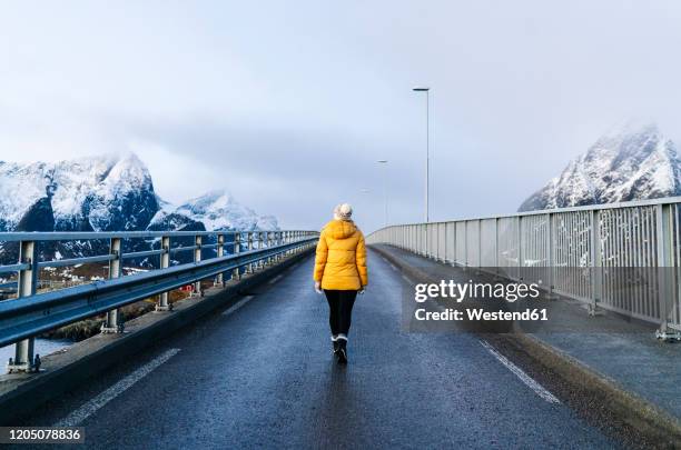 tourist crossing a bridge at hamnoy, lofoten, norway - cruzar puente fotografías e imágenes de stock