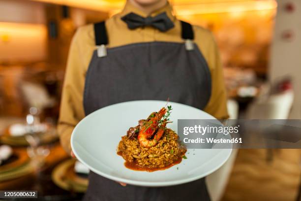 waitress serving paella on white plate - meal expense stock pictures, royalty-free photos & images