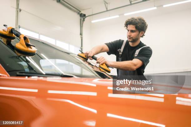 car mechanic in a workshop changing car window - broken windshield stock-fotos und bilder