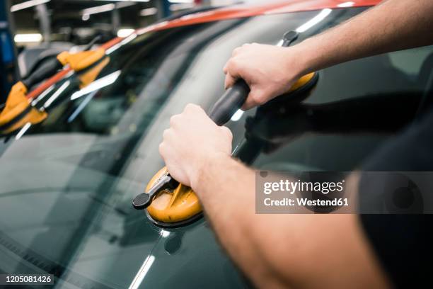 close-up of car mechanic in a workshop changing car window - windshield stock pictures, royalty-free photos & images