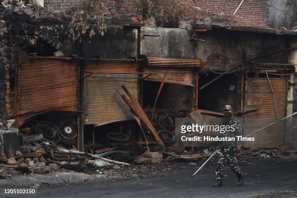 Sashastra Seema Bal personnel walk past burnt and damaged shops, which were allegedly set on fire by miscreants during communal violence last week,...