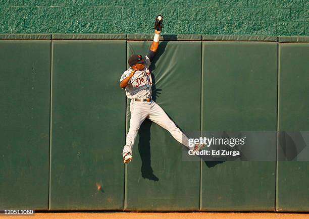 Center fielder Austin Jackson of the Detroit Tigers reaches over the wall as he robs Alex Gordon of the Kansas City Royals of a home run in the first...