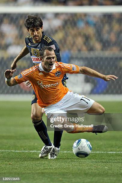 Brad Davis of the Houston Dynamo gets tripped up by Veljko Paunovic of the Philadelphia Union at PPL Park on August 6, 2011 in Chester, Pennsylvania.