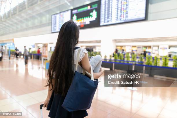 giovane donna asiatica che guarda il tabellone delle partenze al terminal dell'aeroporto - tokyo international airport foto e immagini stock