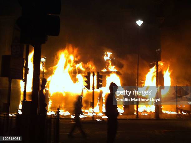 Carpetright store burns on Tottenham High Road after being set on fire by youths protesting against the killing of a man by armed police in an...