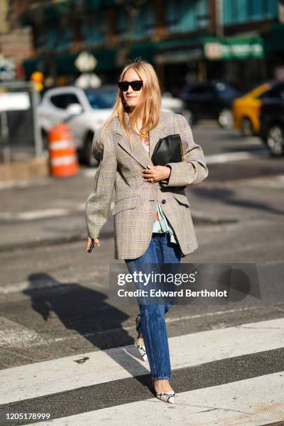 Charlotte Groeneveld wears sunglasses, a checkered oversized blazer jacket, a black clutch, blue denim jeans, pointy snake print shoes, outside Sies...