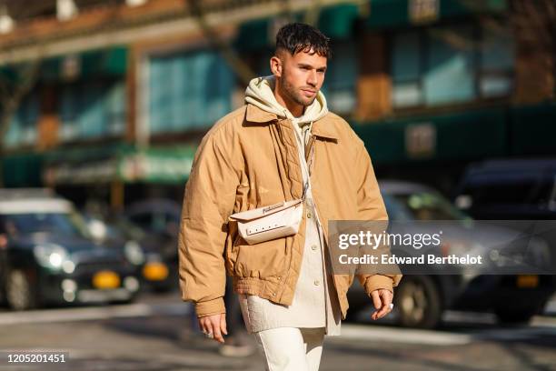 Jean-Sebastien Rocques wears a hoodie sweater, a bomber jacket, a crossbody bag, white pants, outside Sies Marjan, during New York Fashion Week Fall...