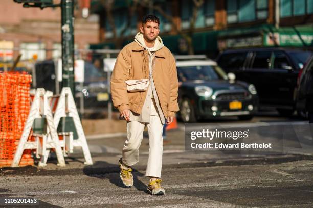 Jean-Sebastien Rocques wears a hoodie sweater, a bomber jacket, a crossbody bag, white pants, sneakers, outside Sies Marjan, during New York Fashion...