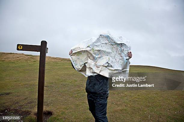 wind blows map into hiker's face - direction stock pictures, royalty-free photos & images