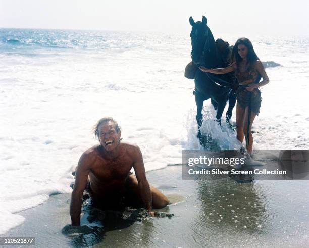 Charlton Heston , US actor, and Linda Harrison, US actress, both wearing animal hides, alongside Kim Hunter , US actress, holding a horse as the tide...