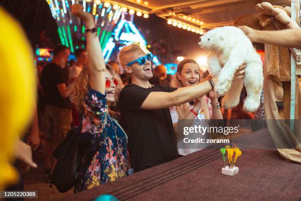 winning teddy bear at amusement park - winnings stock pictures, royalty-free photos & images