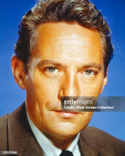 Headshot of Peter Finch , Australian actor, in a studio portrait, against a blue background, circa 1960.