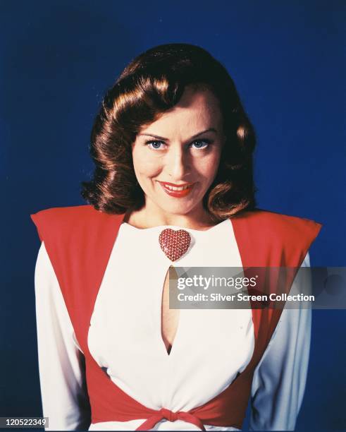 Paulette Goddard , US actress, wearing a red-and-white blouse, with a keyhole neckline, and a large red heart-shaped brooch in a studio portrait,...