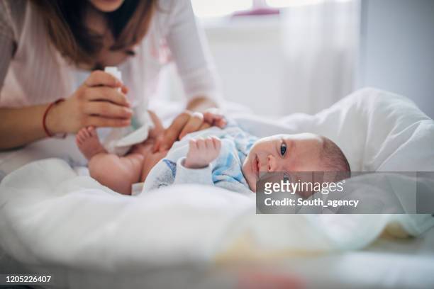 mutter reinigung den nabel von neugeborenen baby junge - bauchnabel stock-fotos und bilder