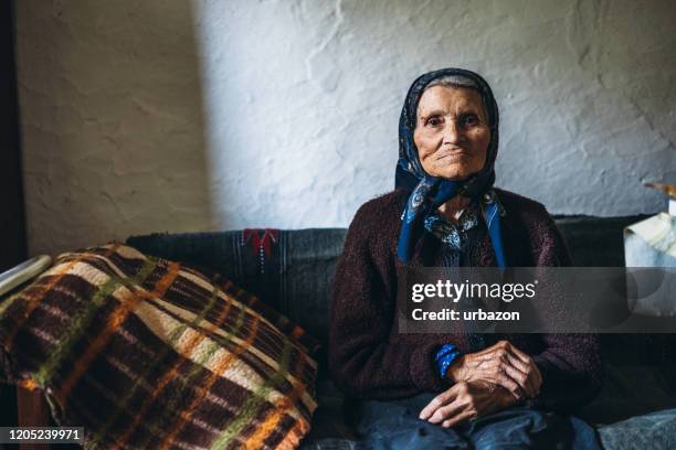 90-jährige frau sitzt auf dem bett - 100 jahre alter mensch stock-fotos und bilder