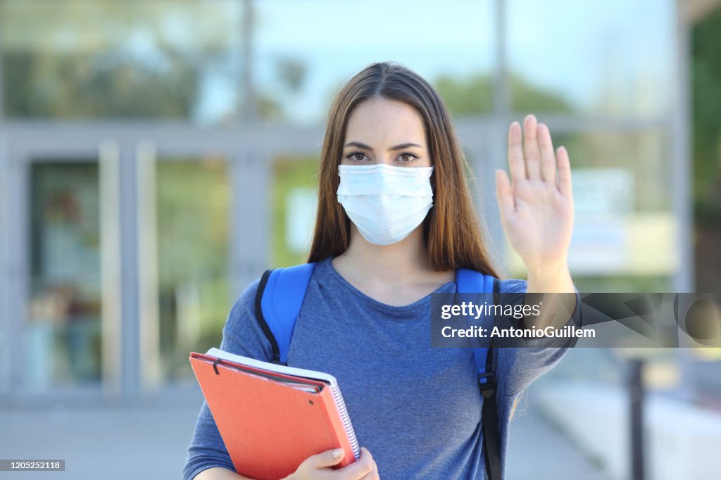 Student with a mask gesturing stop