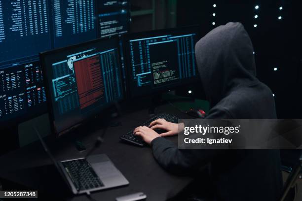 codificación de hackers informáticos en el teclado en un fondo de monitores. - anonymous hacker fotografías e imágenes de stock