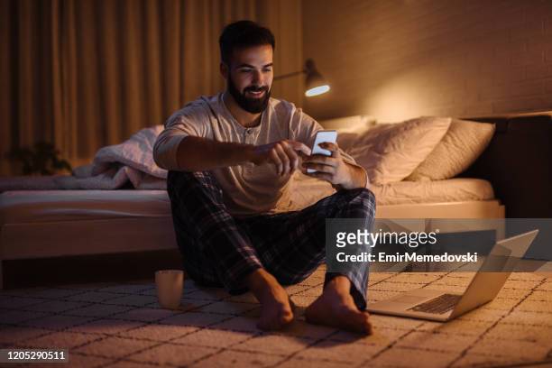英俊的鬍子男子在晚上在臥室使用手機 - men in bed 個照片及圖片檔