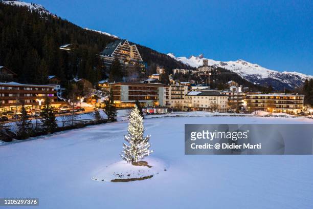 illumoinated fir tree in the middle of a frozen lake in crans montana in the alps in switzerland - crans montana stock-fotos und bilder