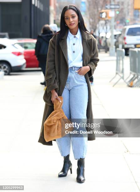 Guest is seen wearing a dark green jacket, light blue shirt, blue jeans, black boots and brown handbag outside of Spring Studios during New York...