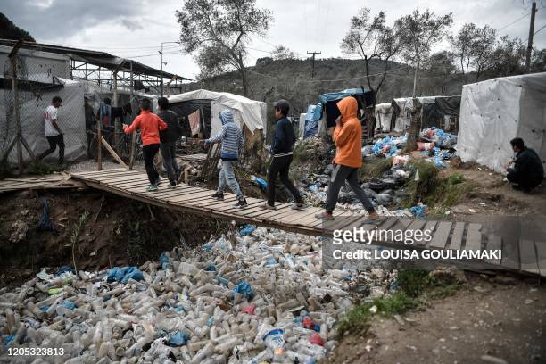 Children walk over a bridge in the Moria migrant camp on the Greek Aegean island of Lesbos on March 5, 2020. - Greece's defence ministry on March 5...