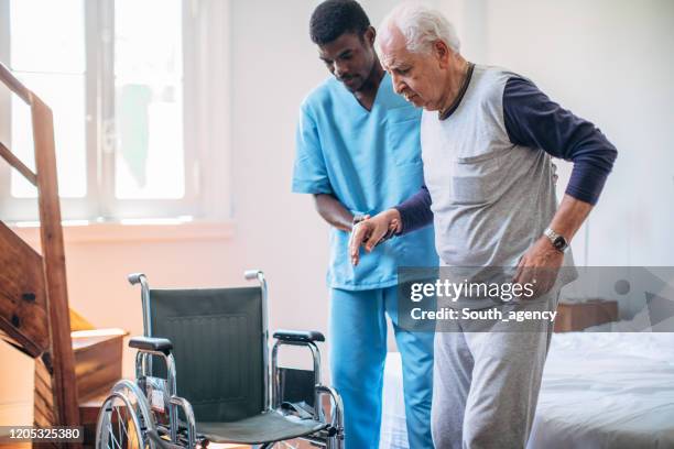 male nurse and senior man - pushing wheelchair stock pictures, royalty-free photos & images
