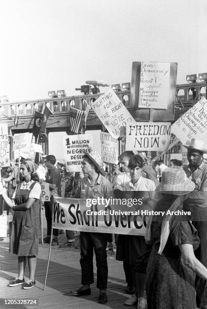 African American and white supporters of the Mississippi Freedom Democratic Party holding signs in front of the convention hall at the 1964...