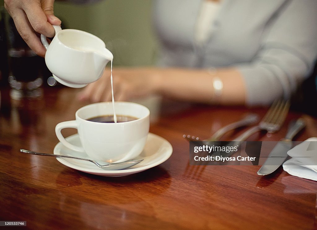 Cream being poured into cup of coffee