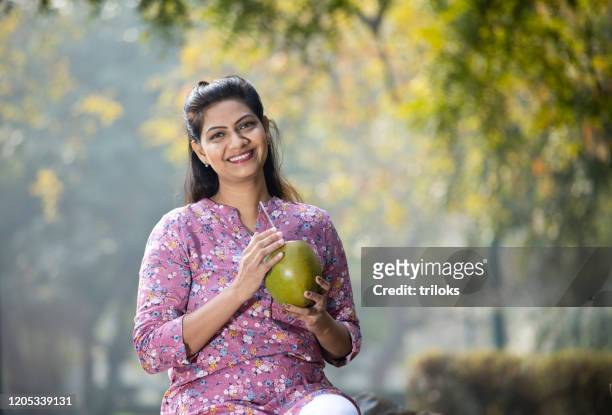 woman drinking coconut water at park - coconut water stock pictures, royalty-free photos & images