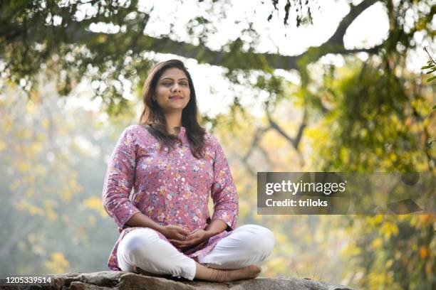 beautiful woman meditating position at park - annual woman stock pictures, royalty-free photos & images