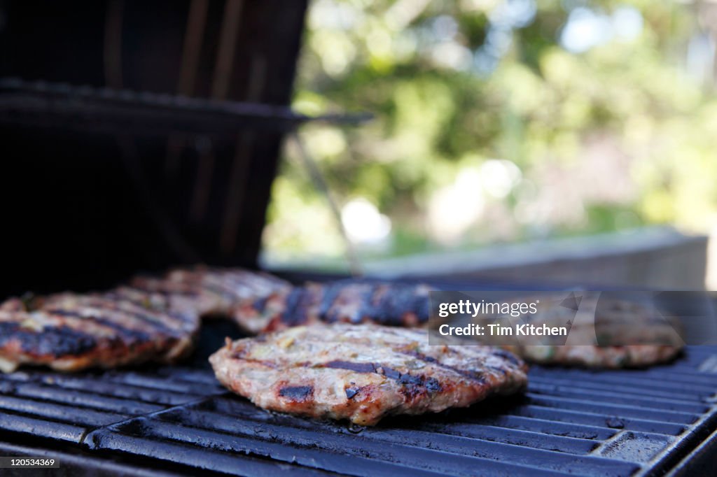 Charred seasoned turkey burgers on outdoor grill